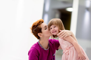 Image showing young mother helping daughter while putting on a dress