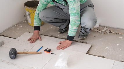 Image showing worker installing the ceramic wood effect tiles on the floor