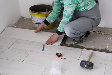 Image showing worker installing the ceramic wood effect tiles on the floor