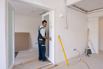 Image showing carpenters installing glass door with a wooden frame