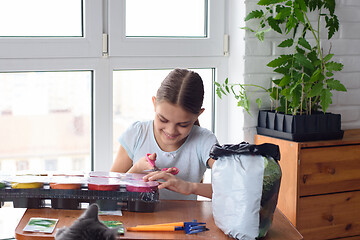 Image showing Girl opens a package with pots for seedlings