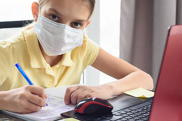 Image showing The sick girl in self-isolation mode does her homework and looked into the frame.