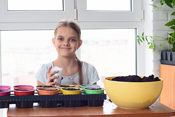 Image showing Girl with bags of seeds and pots of earth sitting at the table