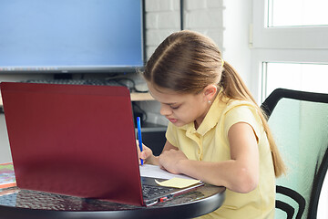 Image showing Girl at home doing homework sitting in front of a laptop screen