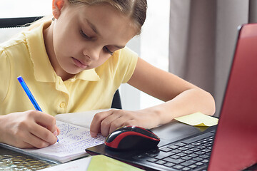 Image showing Closeup of a girl who writes notes in a notebook while studying remotely