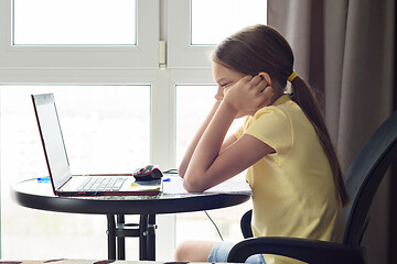 Image showing girl sitting in front of a laptop and thinking about a solution to a problem