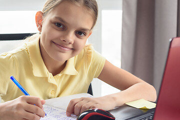 Image showing Closeup portrait of happy girl doing homework in front of computer screen