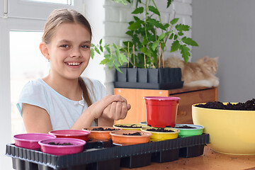 Image showing The girl clutched the seeds in her hands for planting and looks into the frame with a smile