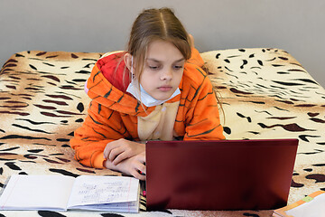 Image showing A sick quarantined girl learns remotely using a laptop