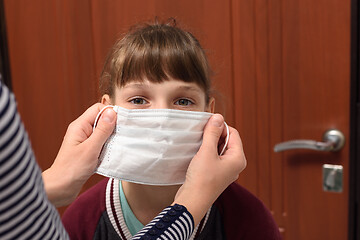 Image showing A girl is put on a medical mask before leaving the house