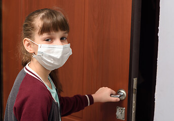 Image showing A girl in a medical protective mask opens the door from the apartment