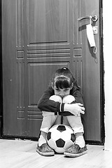 Image showing A girl sits at the front door with a ball, but she is not allowed to go outside during quarantine
