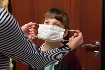 Image showing Mom puts on a child a medical protective mask before leaving the house