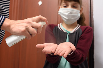 Image showing After a walk on the street, the mother treats her hands with a disinfectant