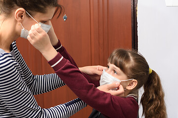 Image showing Mom and child put on each other a protective mask at the front door of the apartment