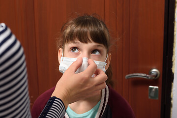 Image showing Mom corrects a protective medical mask on the face of a child