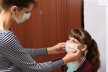 Image showing Mom puts on a child a medical mask before leaving the house