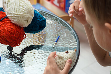 Image showing The girl ties a soft toy to the mouse, sews eyes