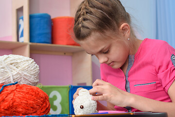 Image showing Girl embroiders a soft toy with her own hands.