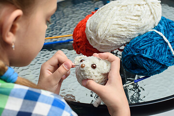 Image showing Girl sews on the eyes of a homemade soft toy mouse