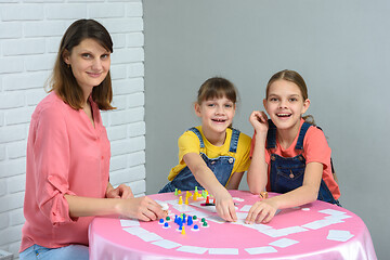 Image showing Children and a young mother sit at a table and play a board game