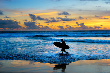 Image showing Surfer with surfboard at sunset