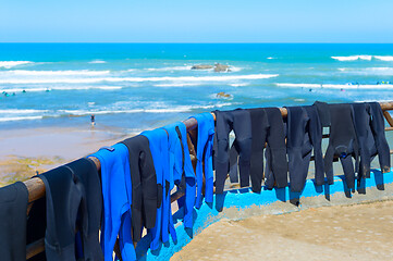Image showing Surfers wetsuits drying on beach