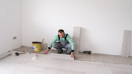 Image showing worker installing the ceramic wood effect tiles on the floor