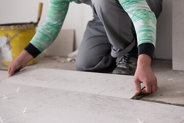 Image showing worker installing the ceramic wood effect tiles on the floor