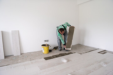 Image showing worker installing the ceramic wood effect tiles on the floor