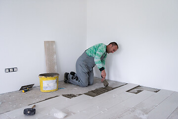 Image showing worker installing the ceramic wood effect tiles on the floor