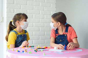 Image showing Two girls in protective medical masks in quarantine play board games