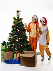 Image showing Two girls stand by the Christmas tree and hold festive tinsel in their hands.