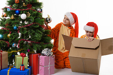 Image showing Dona girl takes the ball from the Christmas tree, the other puts the toys in the box