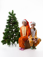 Image showing Two girls sitting on a box with toys near an artificial Christmas tree