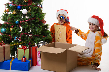 Image showing The girl hung Christmas balls on her sister\'s hat and looked into the frame with a smile