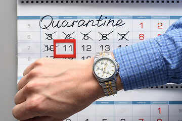 Image showing The hand on which the watch is worn, in the background a calendar with the inscription Quarantine