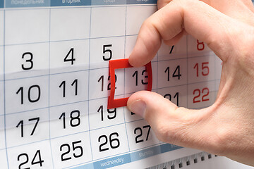Image showing The hand on the calendar moves the pointer from the twelfth to the thirteenth