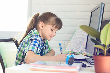 Image showing A girl writes with a pen in a notebook, learning remotely without leaving home