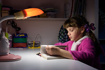 Image showing Girl at home doing homework under the light of a table lamp