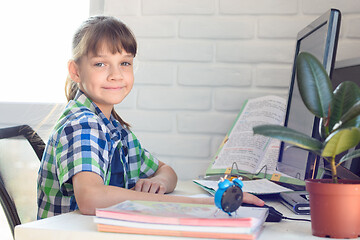 Image showing The girl does homework at the table, looked into the frame