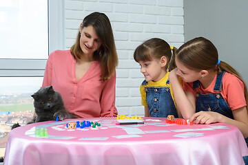 Image showing The family watches as the cat plays a chip from the table from the board game