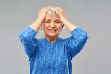 Image showing stressed senior woman holding to her head