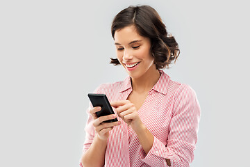 Image showing young woman in striped shirt using smartphone