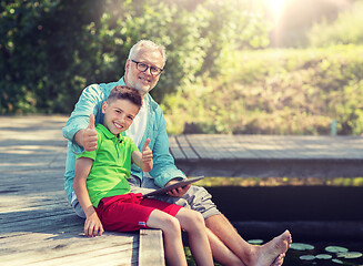 Image showing grandfather and boy with tablet pc on river berth