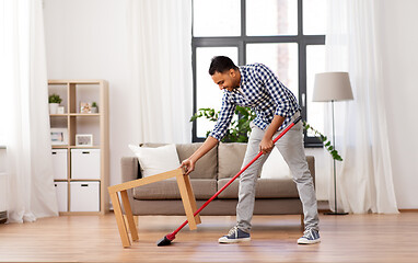 Image showing man with broom cleaning floor at home