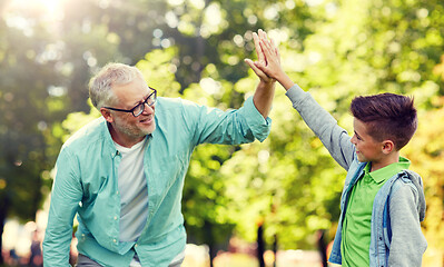 Image showing old man and boy making high five at summer park