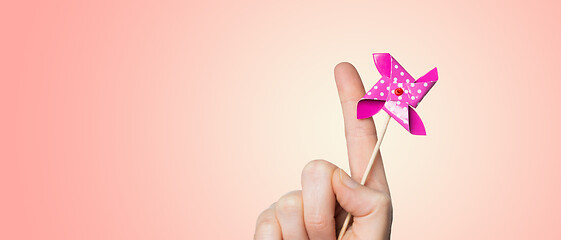 Image showing close up of hand holding pinwheel toy over pink