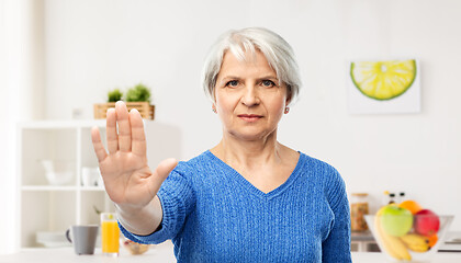 Image showing senior woman making stop gesture in kitchen