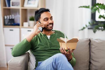 Image showing smiling indian man eating takeaway food at home